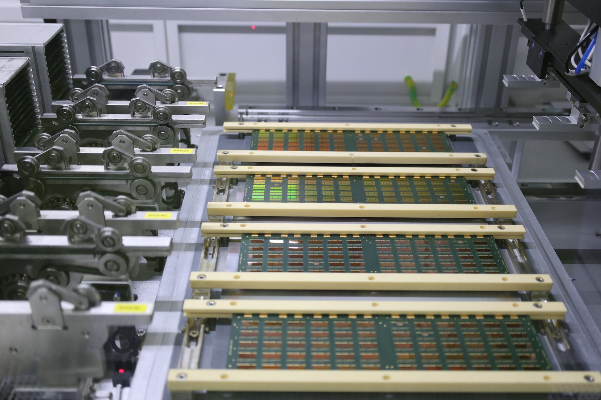 Industrial machine frame holding rows of green circuit strips and gold rails